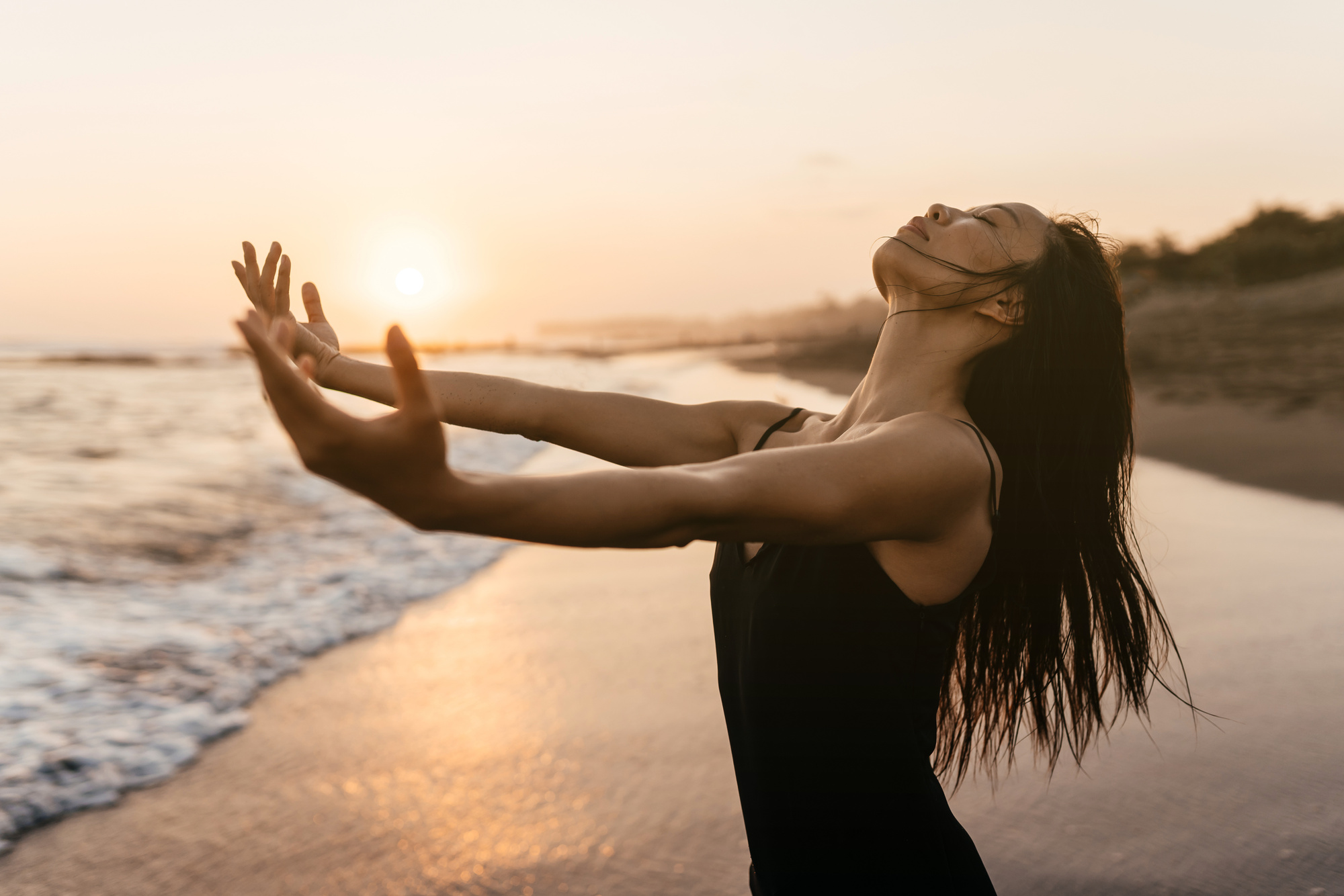 Freedom Chinese woman feeling free dancing at beach sunset.